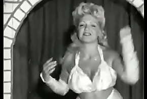 Curly blonde with huge tits takes part in an erotic performance of the 60s