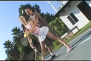 Cheerful brunette in a short skirt gives a guy a blowjob on the tennis court